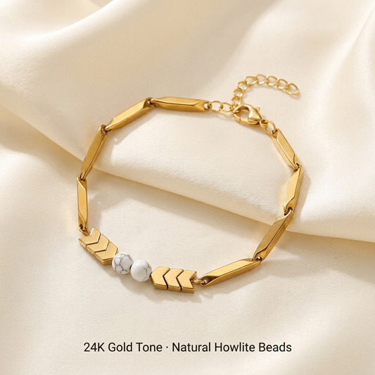 24K gold-tone rice chain bracelet with two white Howlite beads laid on cream silk