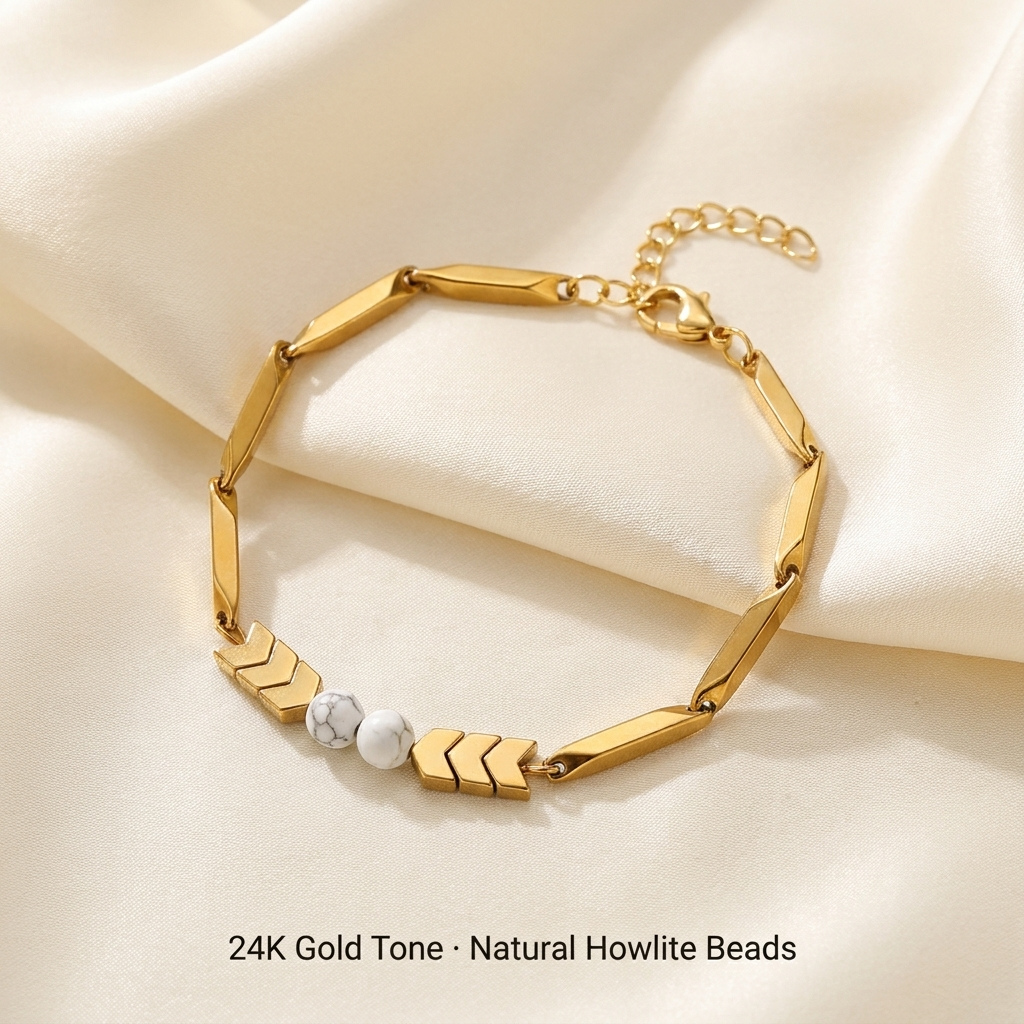 24K gold-tone rice chain bracelet with two white Howlite beads laid on cream silk