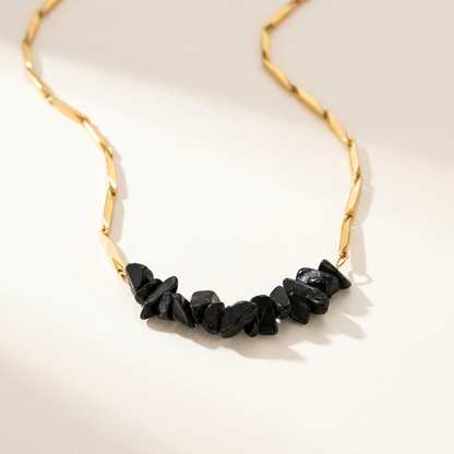 Gold-tone Obsidian rice chain pendant necklace laid on a soft neutral surface