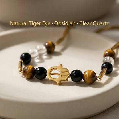 Macro close-up of the golden Hamsa charm flanked by Tiger Eye, Clear Quartz and Black Obsidian beads
