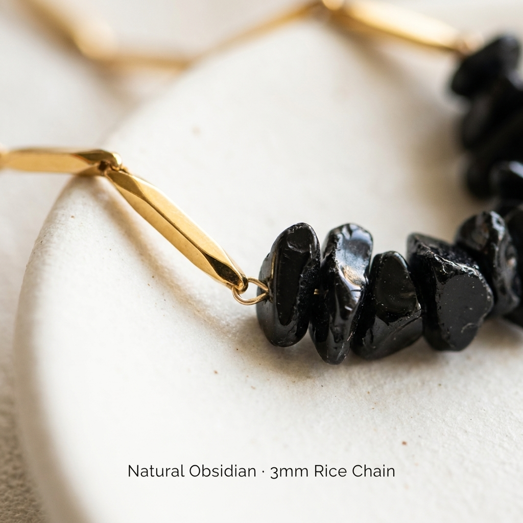 Macro close-up of black Obsidian crystal chips and 3mm gold-tone rice chain links