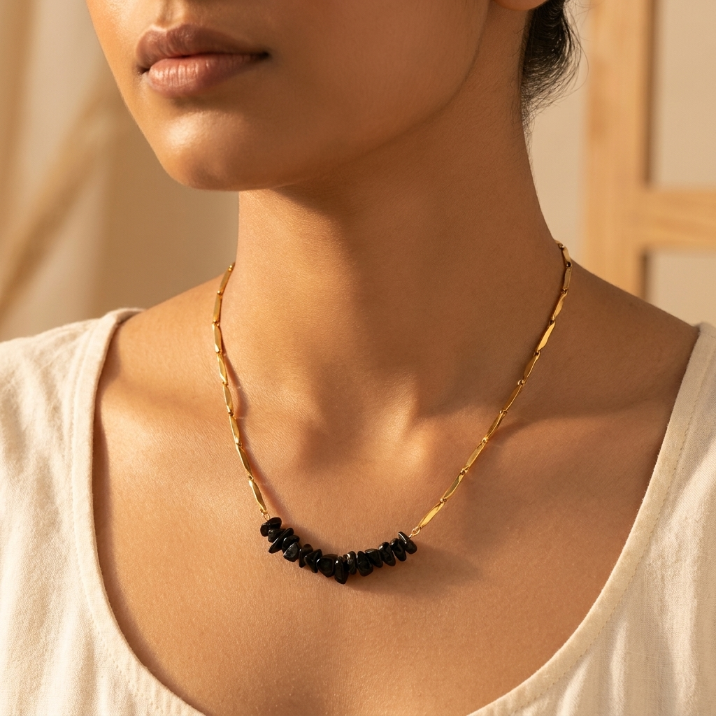 Woman wearing the gold-tone Obsidian rice chain necklace, styled minimally