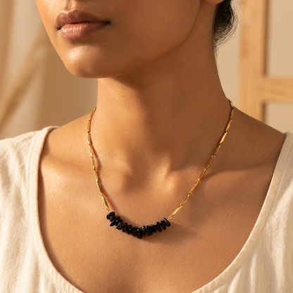 Woman wearing the gold-tone Obsidian rice chain necklace, styled minimally