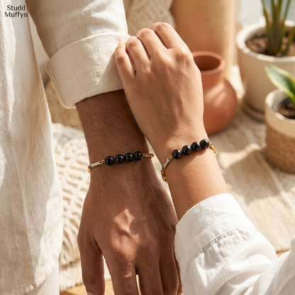 A man and a woman both wearing the unisex Black Obsidian dual-tone bracelet on their wrists in a bright airy setting